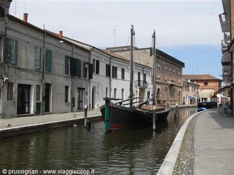 Old sailing boat moored along Comacchio canal between colorful houses