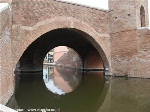 Brick bridge over Comacchio canal, arches reflected in still water