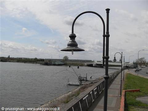 Cast-iron street lamps along the river walkway, bridge in the distance