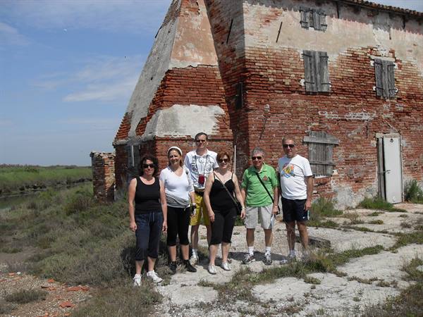 Group of tourists in front of an old red brick farmhouse with shuttered windows