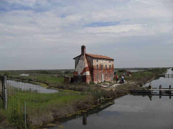 Old brick house in the Comacchio lagoons, visitors by the canal
