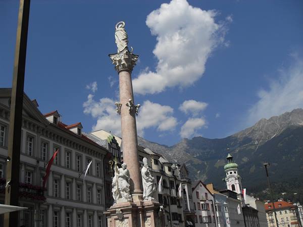 Saint Anne Column in Innsbruck, marble statues and green spire beneath the Alps