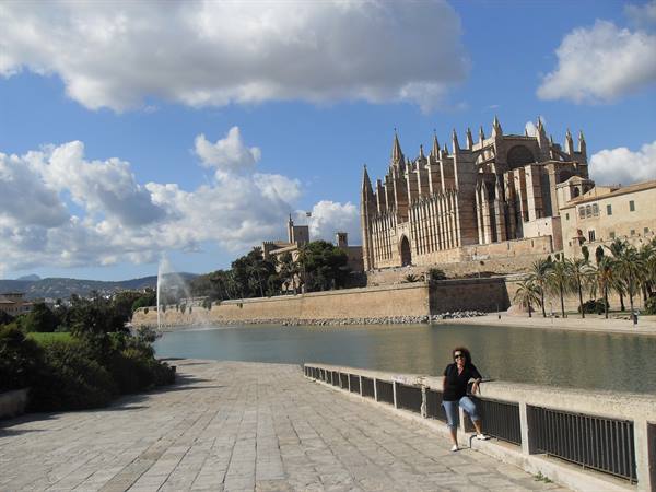 Woman leaning on railing in front of Palma de Mallorca cathedral and pond