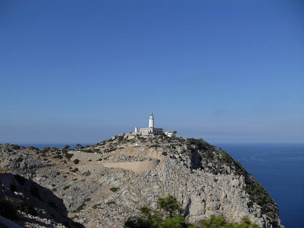 White lighthouse on the rocky cliffs of Cap de Formentor above the sea