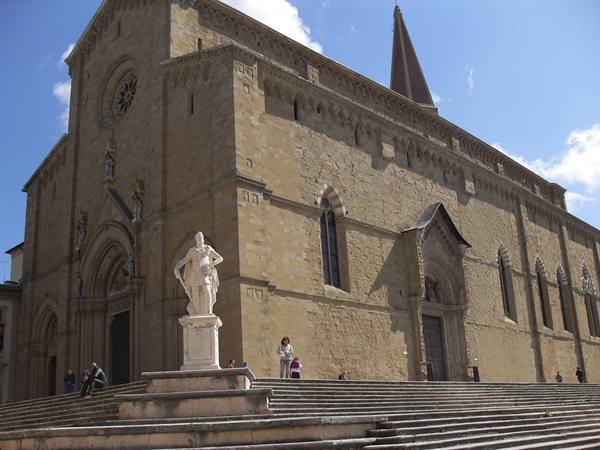 Marble statue on the steps in front of Arezzo stone cathedral