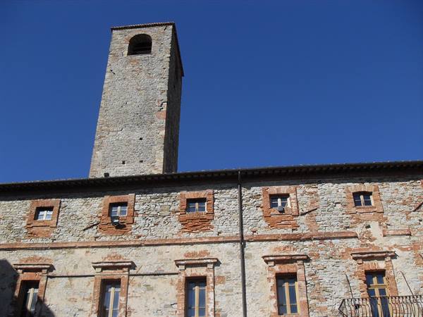Medieval stone tower above a brick-windowed palace under clear blue sky