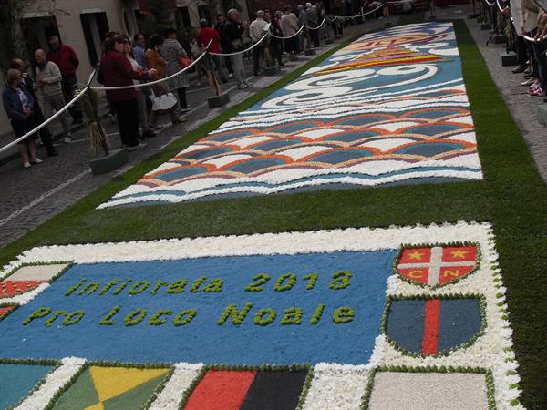 Infiorata 2013 flower carpet in Noale, petals arranged along the street, visitors behind ropes