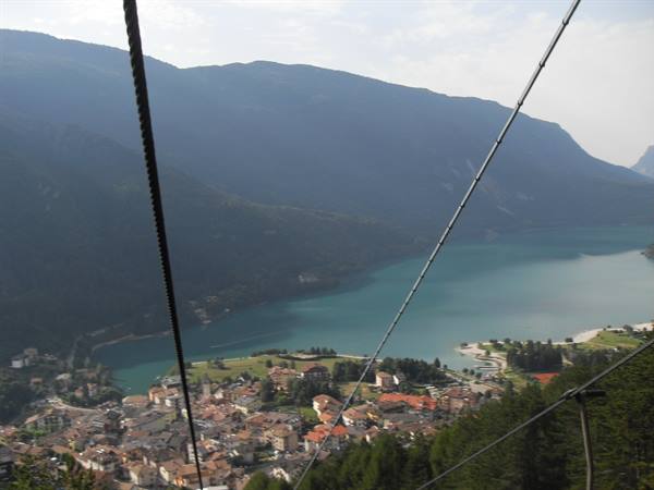 Cable car wires above the village and Molveno lake between green mountains