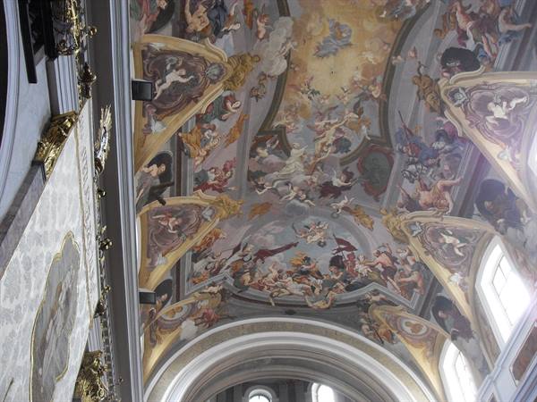 Baroque ceiling fresco with angels and figures in a church lit by windows