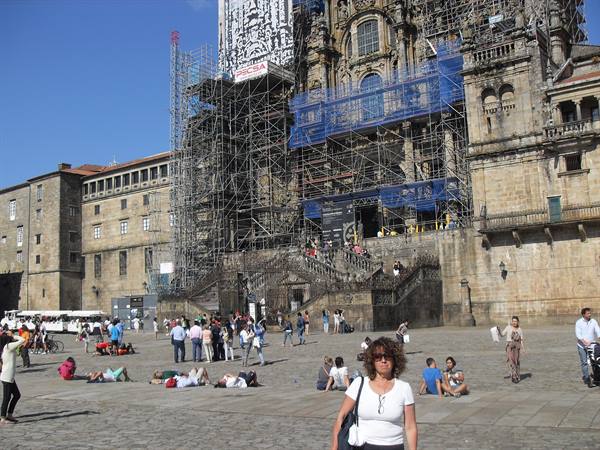 Tourists on the square in front of Santiago cathedral covered by scaffolding