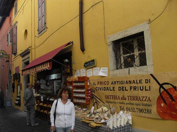 Woman in front of Osteria alla Terrazza stall with cheeses and cured meats in Cividale del Friuli