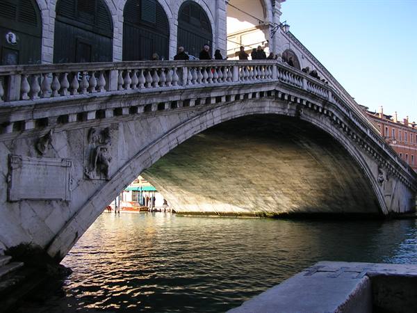 Tourists crossing the marble arch of Rialto Bridge in Venice