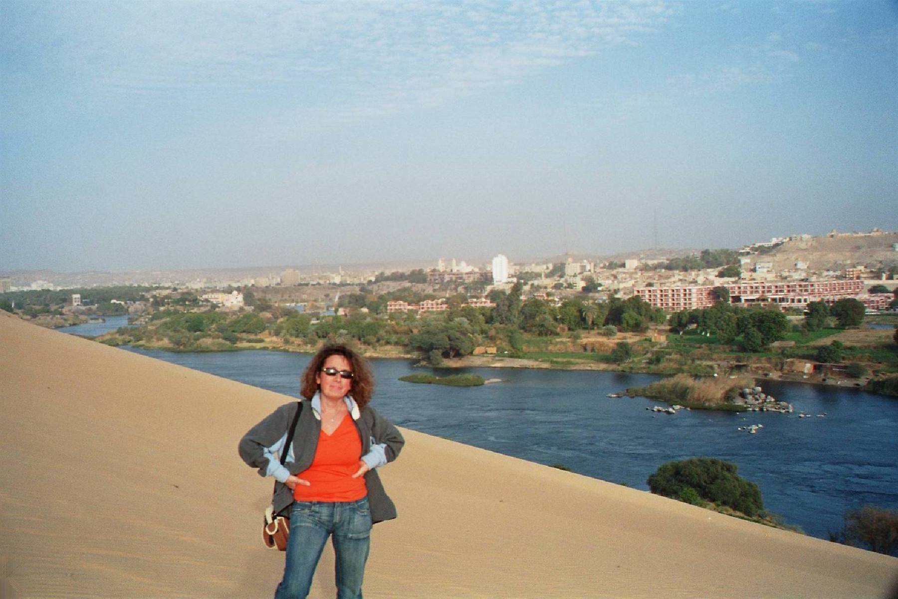 Woman in orange top on the sand dune above the Nile, Aswan