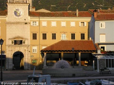 Stone clock tower and fountain in Koper's square under golden evening light