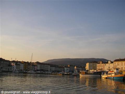 Cres harbor at dawn, moored boats and waterfront houses reflecting on water