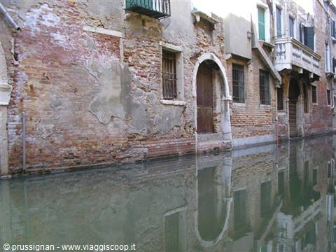 Weathered brick facades reflected in a quiet Venice canal