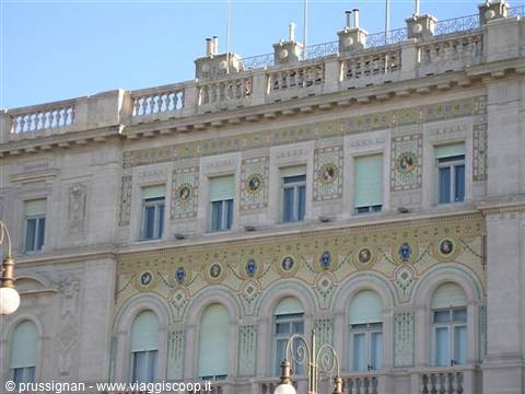Light stone facade decorated with mosaics and medallions under a blue sky