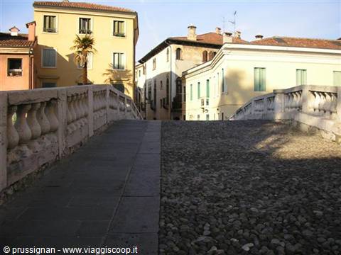 Stone bridge with balustrade beside colorful old houses