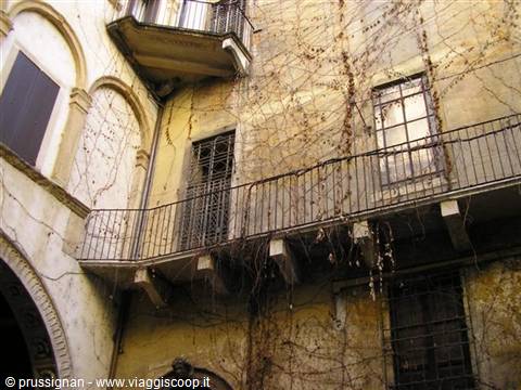 Iron balcony on plastered facade covered with dry ivy