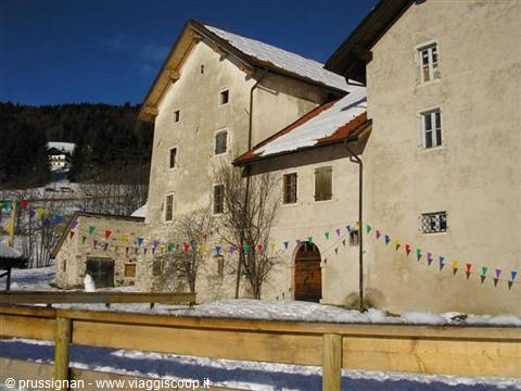 Old plastered houses in snow with colorful bunting, mountain and firs
