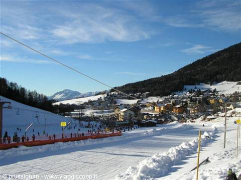 Skiers on the snow beneath a chairlift at a snowy alpine ski resort