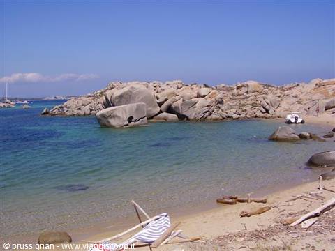 Beach with granite boulders and turquoise water, a stranded boat on the sand
