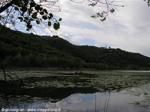 Canoe on a lily-covered lake, wooded hills and cloudy sky