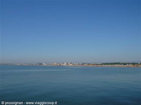 blue sea with distant sandy beaches and buildings under clear sky