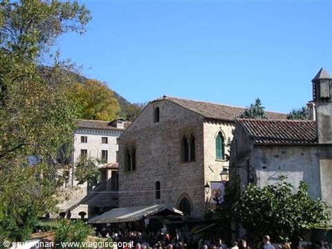 Crowd on a square before a stone building with pointed windows in Scanno