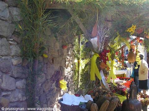 Market stall with nuts and yellow ribbons under pine pergola, stone wall
