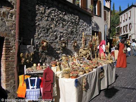 Craft and sweets stall beneath stone walls, woman in red costume