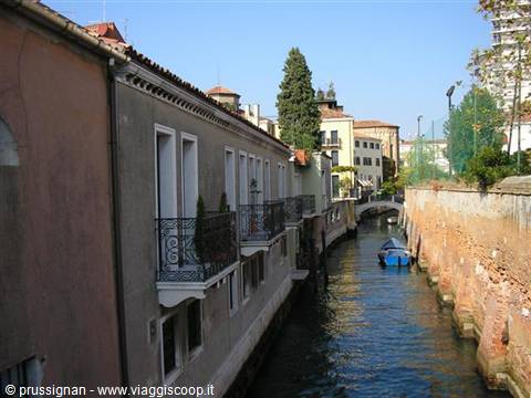 Canal in Venice with buildings, wrought iron balconies and a blue boat