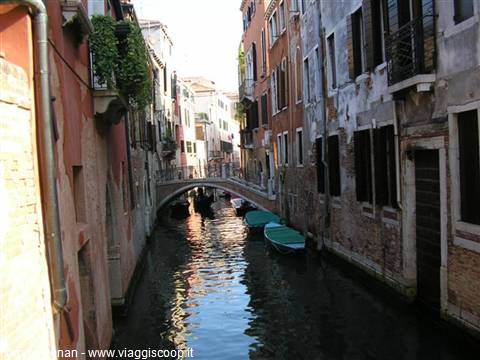 Venice canal with moored boats and a small bridge between old facades