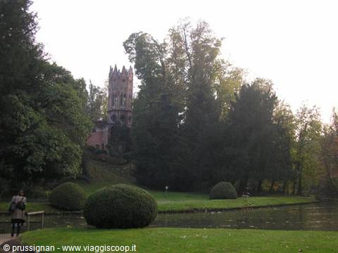 Gothic revival tower among trees at Parco Giardino Sigurtà, with rounded hedges and pond