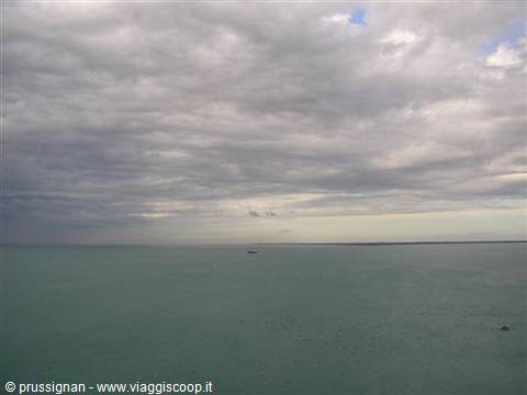 Grey clouds over the green sea with a tiny boat