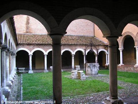 Romanesque cloister with marble columns, brick arches and a stone well on the lawn