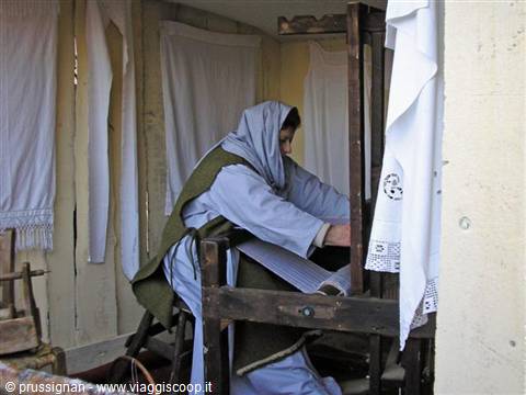 Woman in traditional costume weaving on an old wooden loom indoors