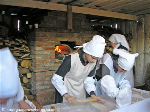 Women in historical costume baking bread in a brick wood-fired oven