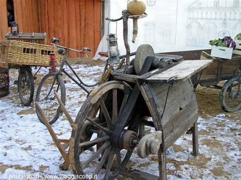 Antique wooden pedal grinding wheel with stone, vintage bicycle and wicker basket on snow