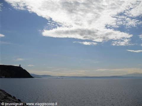 calm sea under scattered clouds, hill with tower on the left