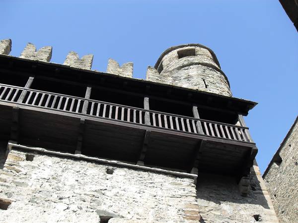 Wooden balcony and crenellated tower of Fénis Castle against blue sky