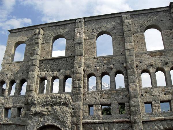 Roman theatre of Aosta, stone wall with arches against a cloudy sky