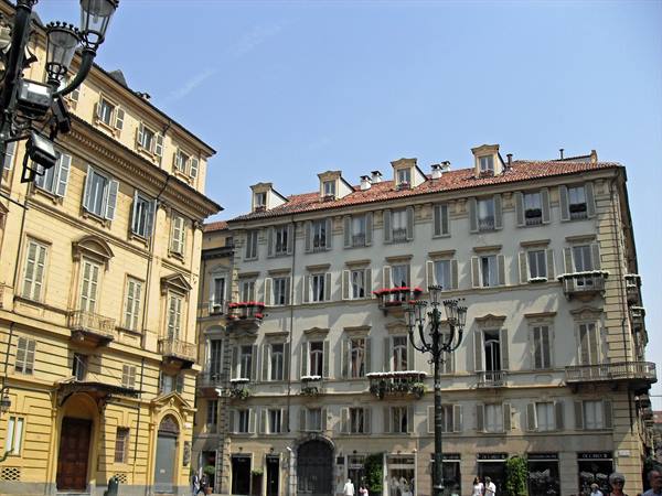 Historic buildings with flowered balconies and lampposts in a Turin square