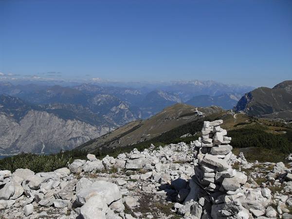 Limestone cairn on an alpine ridge, blue mountains and clear sky