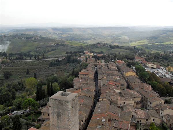 Tiled rooftops and medieval tower in San Gimignano among rolling hills
