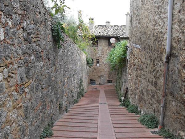 Brick staircase between stone walls, old houses with tile roofs, soft daylight
