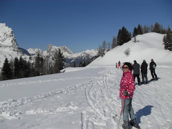 Skier in pink jacket with poles on snowy slopes near jagged peaks