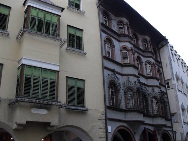 Arched arcades with projecting bay windows and green shutters