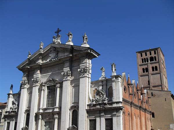 Marble facade of Mantua Cathedral with statues, beside the brick bell tower