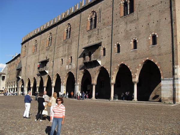 Tourists walk in front of the Palazzo del Capitano in Mantua, brick arcades